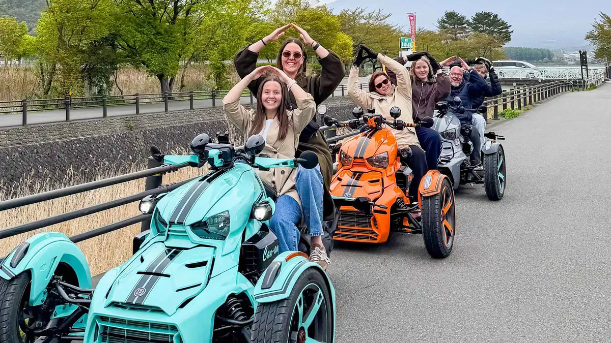 An open three-wheel trike parked on the Lake Kawaguchi shore road with Mount Fuji behind on a scenic trike tour from Lake Kawaguchi, Japan
